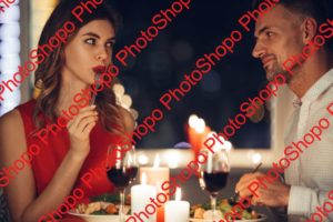 Young woman eating and flirting with her man while have romantic dinner